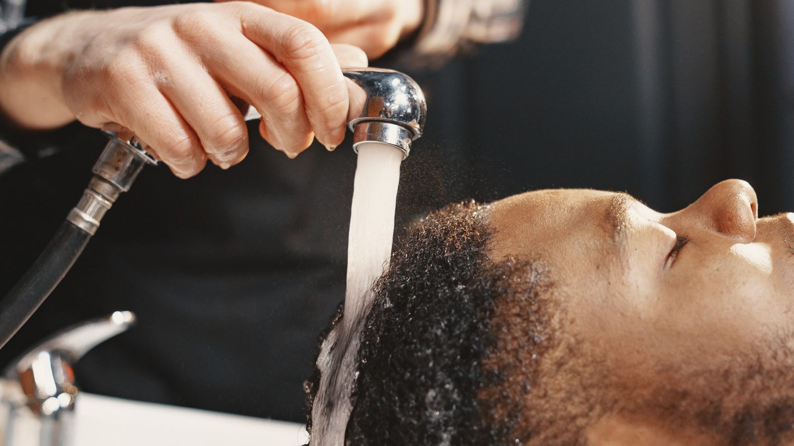Man having his hair washed at a salon, scalp care a trichologist in Southend-on-Sea supports
