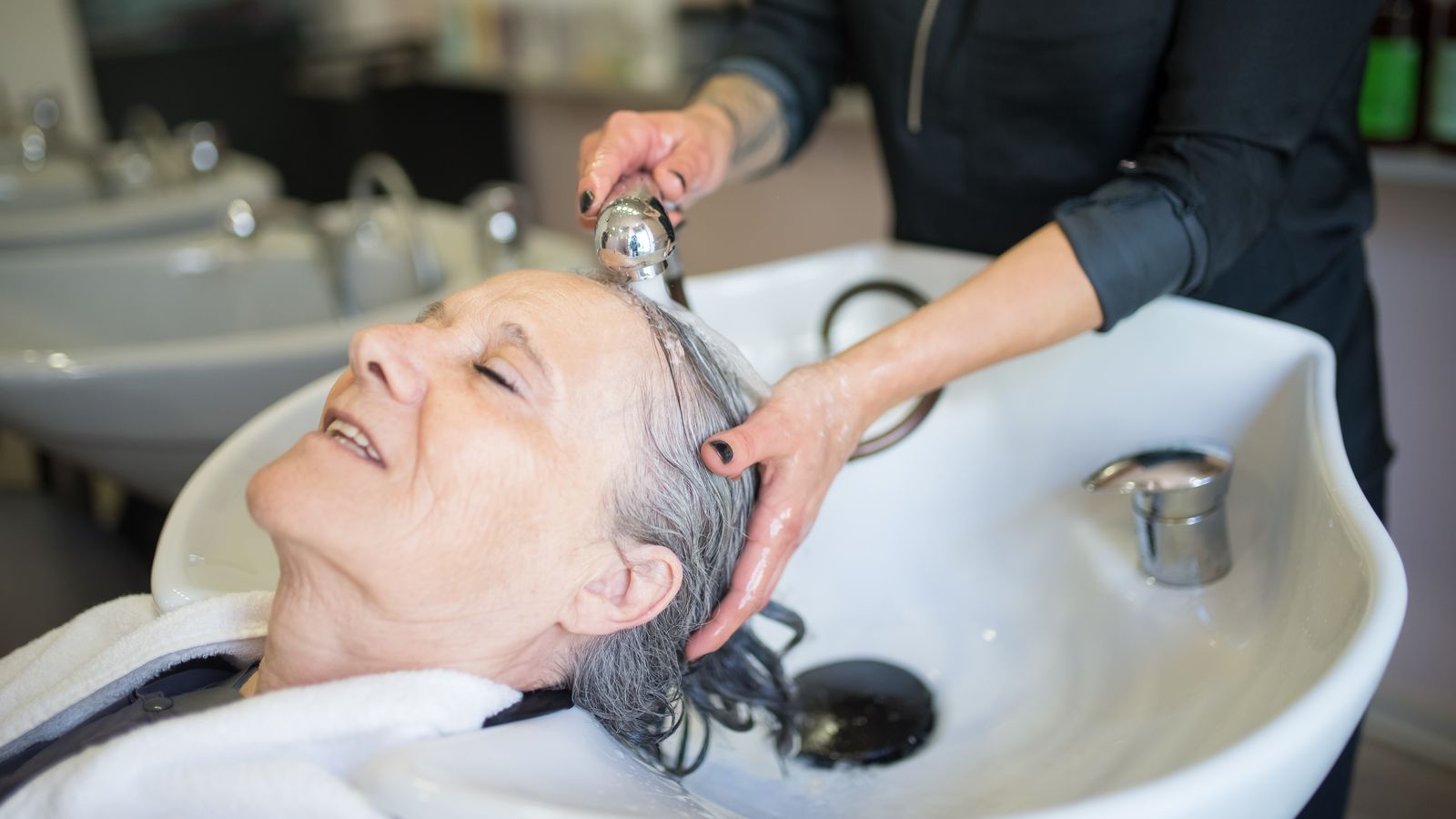 Older woman having a soothing salon hair wash, the gentle scalp care a trichologist in Warrington advises
