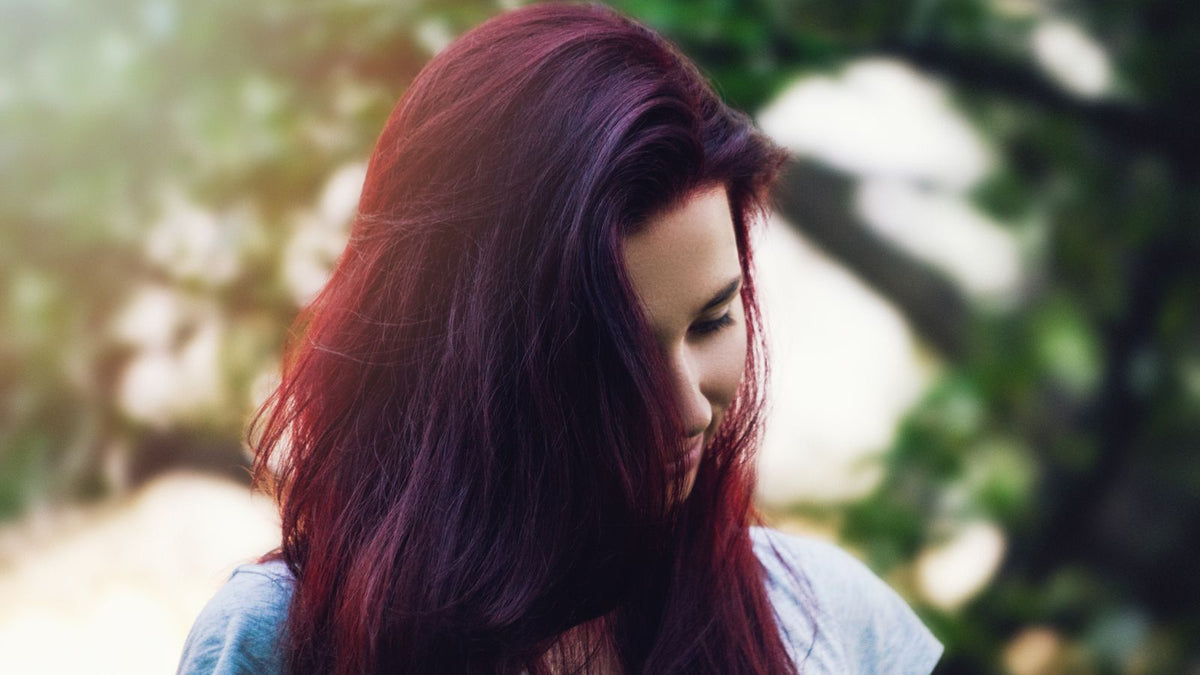Woman with long deep red hair outdoors, the warm tone plant dyes give, for readers searching trichologists in Banbury