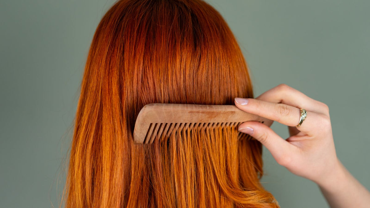 Long red hair combed with a wooden comb, the parting check trichologists Macclesfield describe to clients