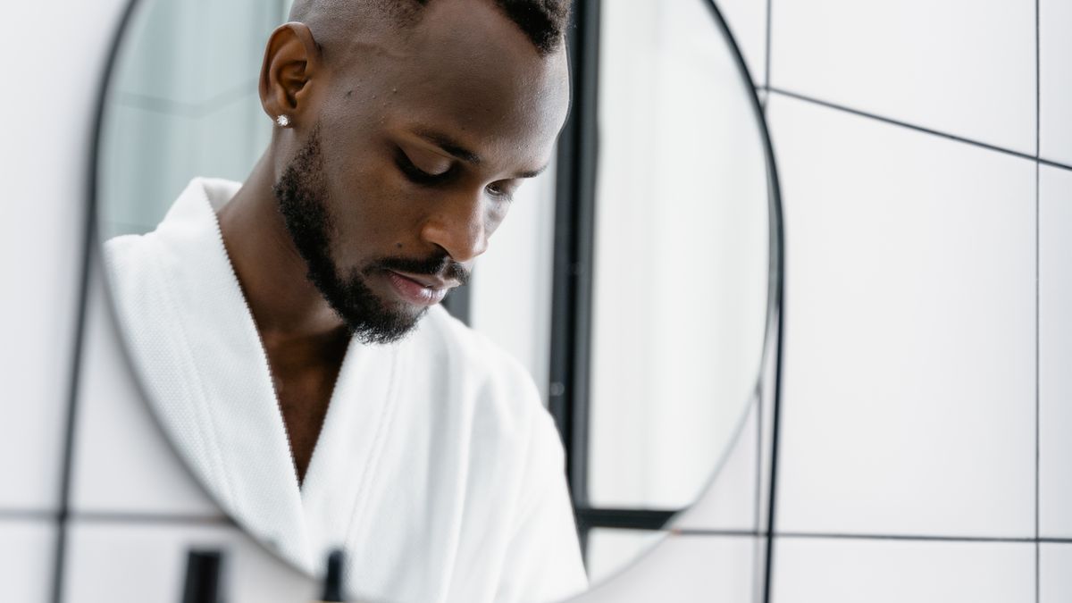 A man studying his hairline in a bathroom mirror before seeing trichologists Newcastle upon Tyne
