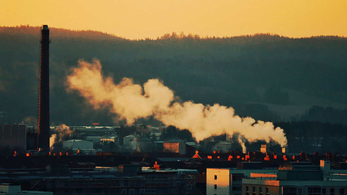 Factory chimney smoke drifting over a hillside town at sunset, the kind of view behind many trichologists Scunthorpe searches about air pollution and hair