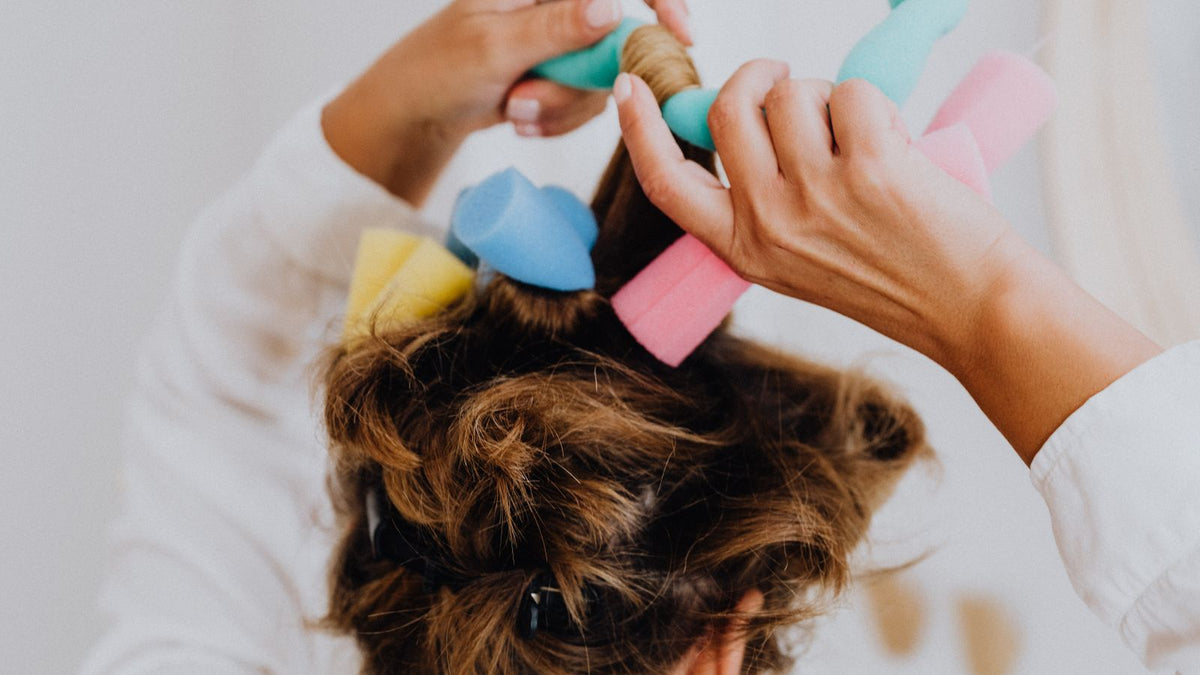 Woman setting her hair in soft foam rollers for heatless curls, a gentle styling question for trichologists Wokingham readers with fine hair