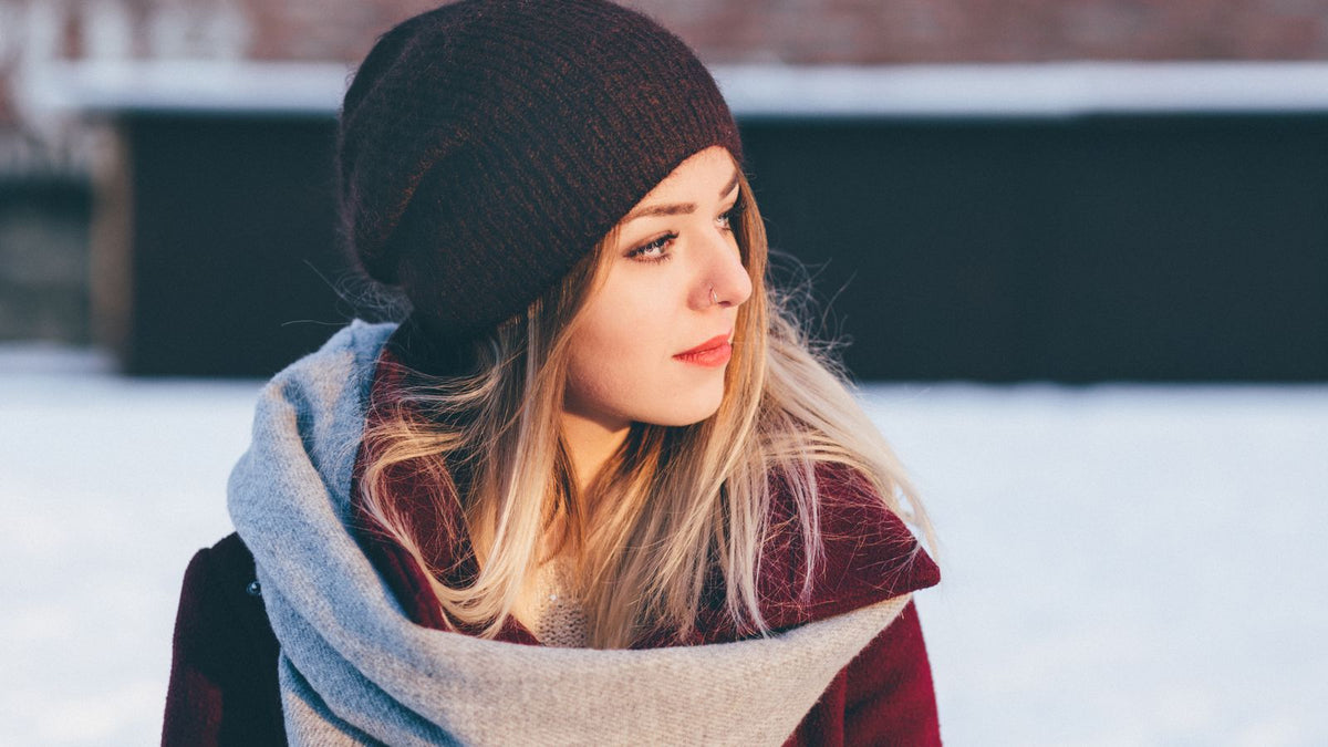 Woman in a knitted beanie and scarf outdoors in winter, the season many people search for trichologists Worcester about dry, static hair
