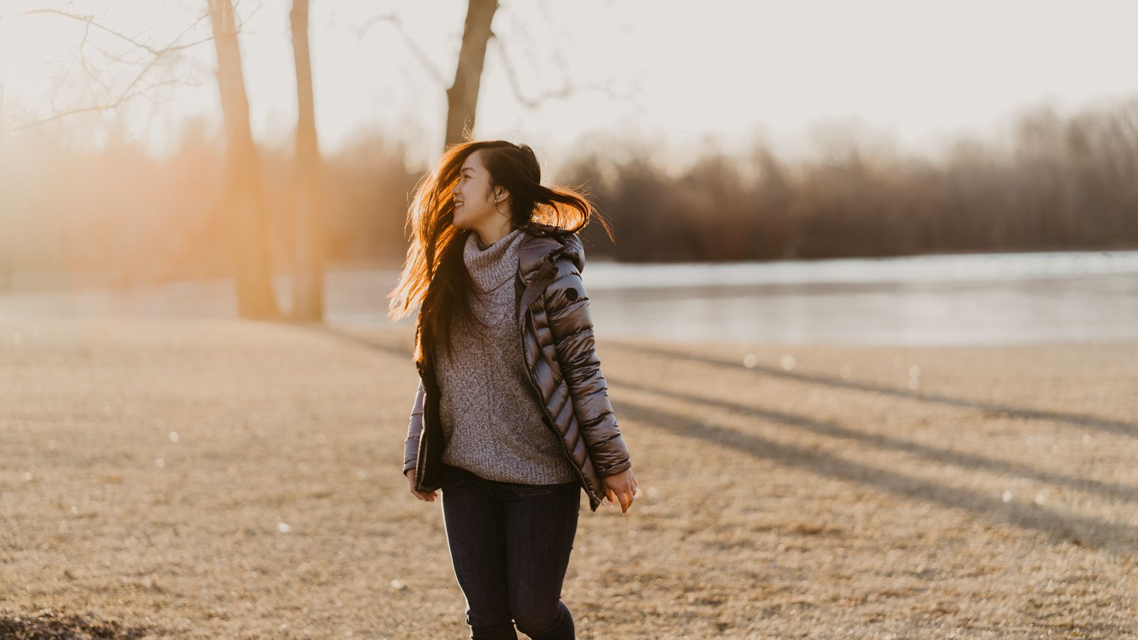 Woman walking in a sunny winter park, the weak daylight behind widespread vitamin D deficiency