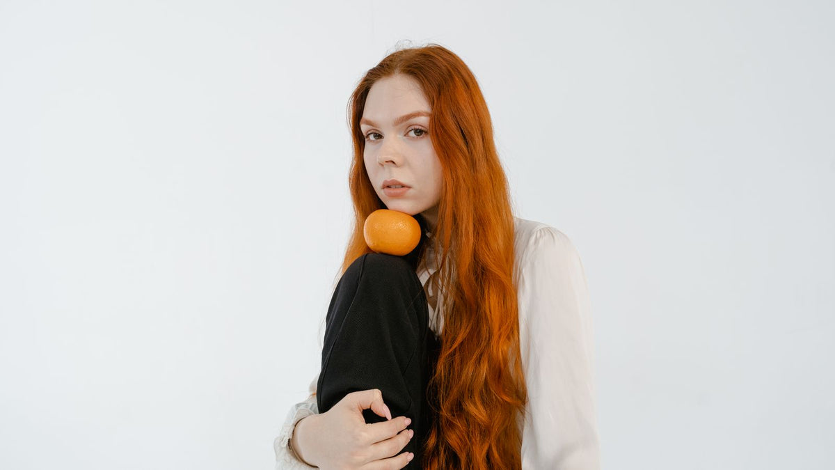 Woman with long glossy red hair, showing the ways to support healthier hair in practice