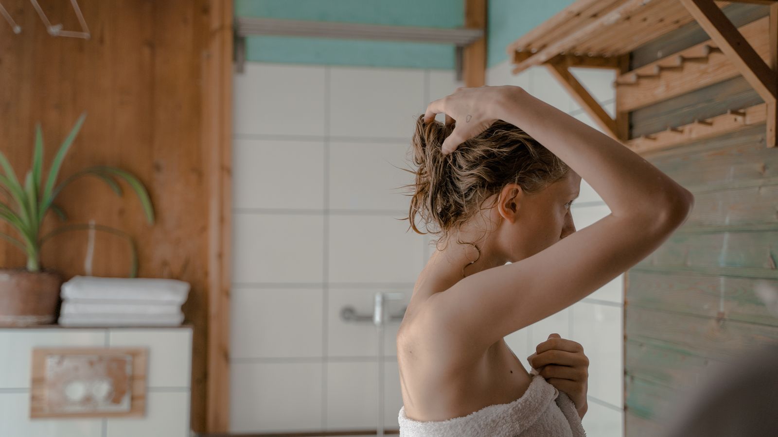 Woman in a towel gently handling her wet hair after the shower