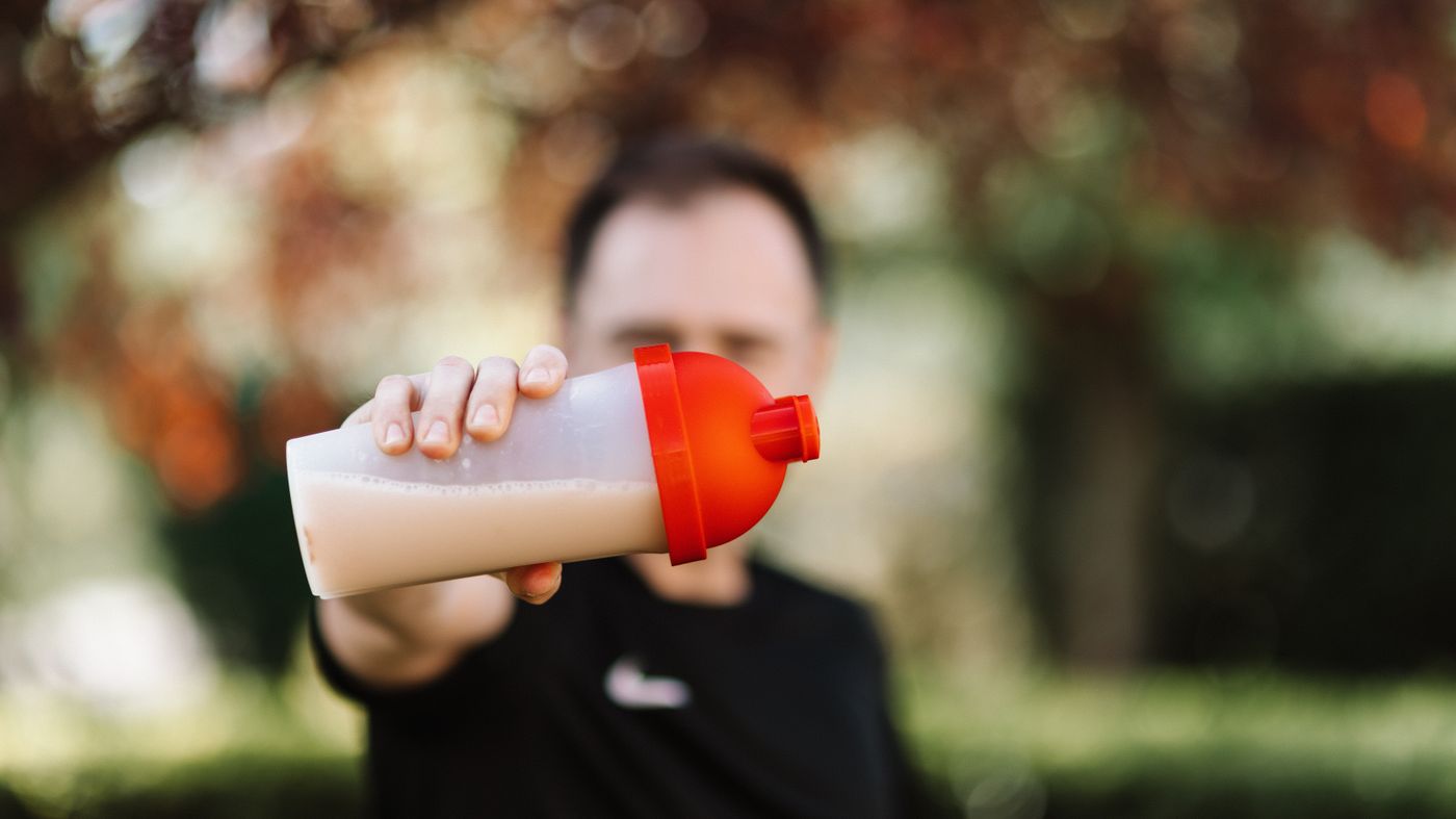 Man drinking a whey protein shake outdoors, illustrating the question of whether whey protein is bad for your liver