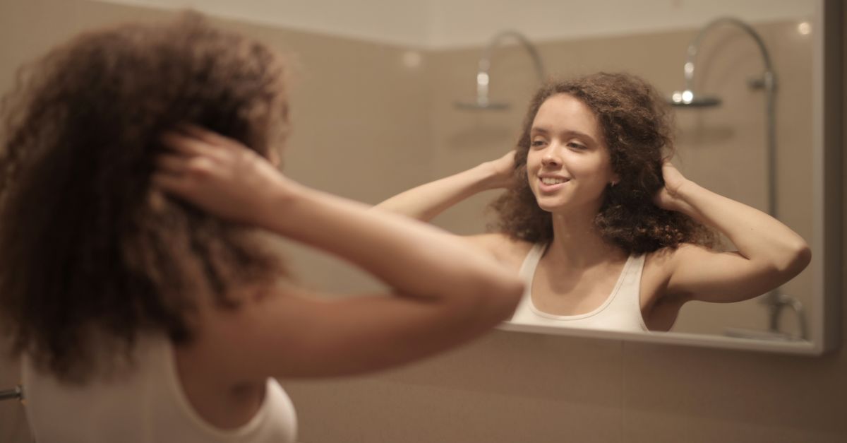 Woman checking her hair in the mirror, wondering why results fade after the first few months