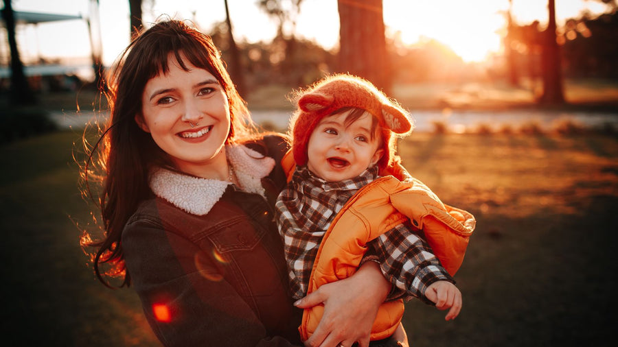 Mother and baby smiling outdoors near the first birthday, when postpartum shedding usually settles
