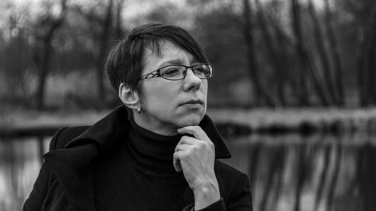 Thoughtful woman outdoors by a lake, thinking about seeing an alopecia areata dermatologist
