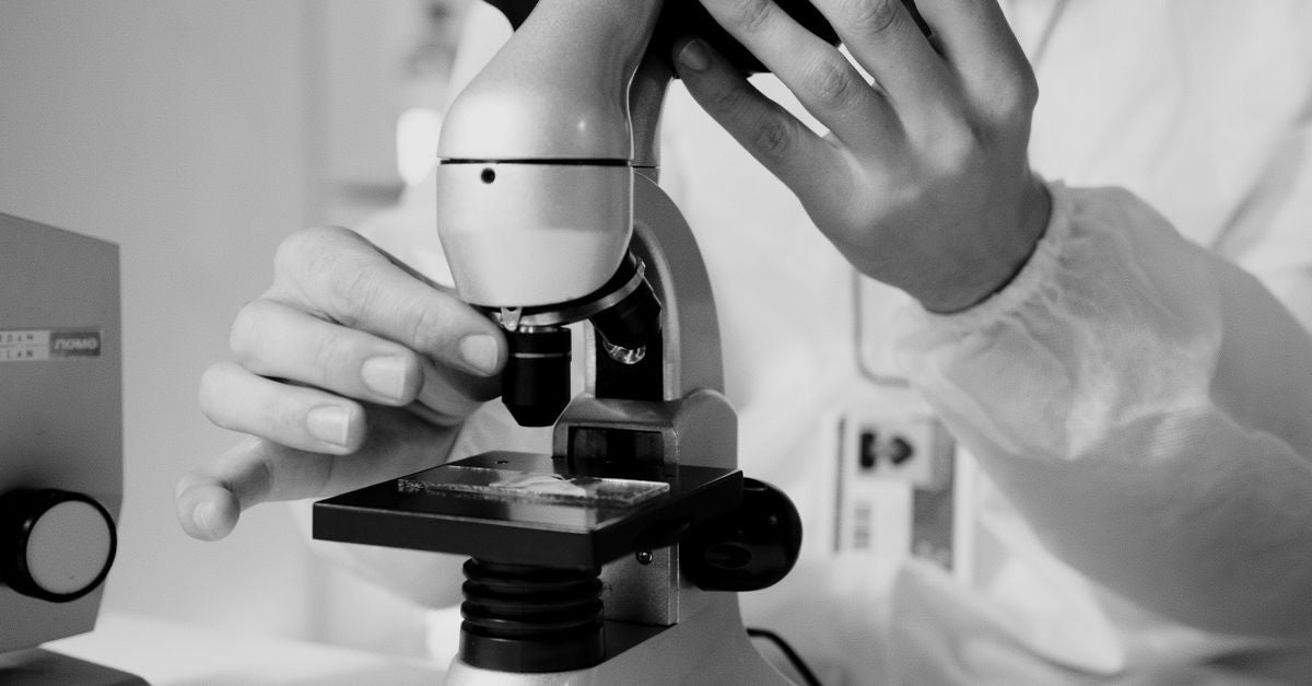 Scientist at a microscope researching aromatase activity and hormones