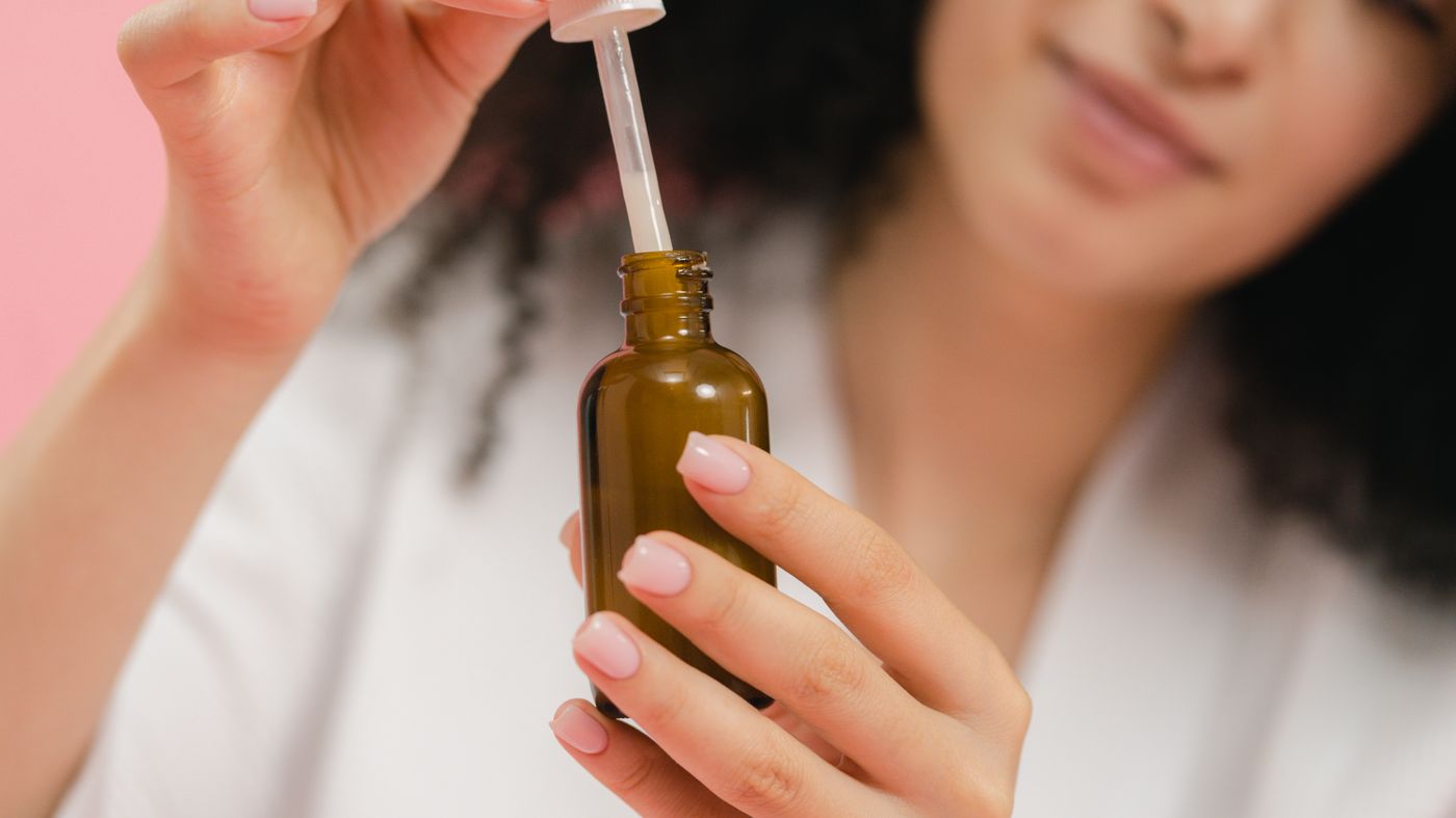 Woman using a dropper bottle of serum as part of a budget skincare routine
