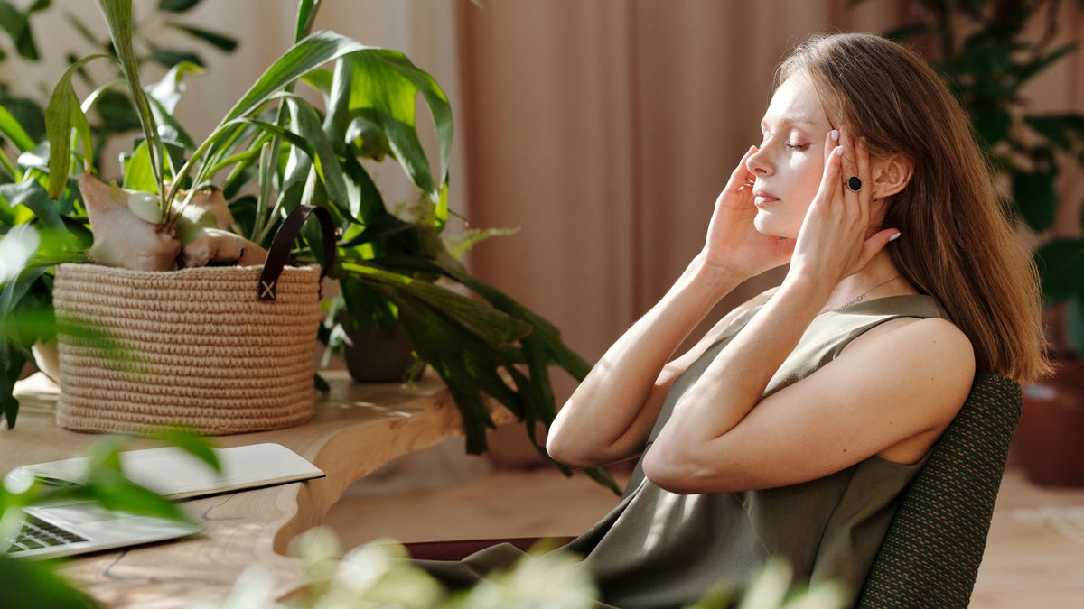 Woman massaging her temples in a bright room, thinking about scalp capillary density