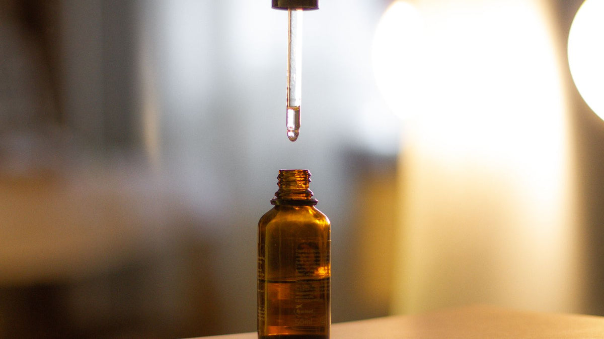 Amber dropper bottle of castor oil for hair growth, applied a few drops at a time along the scalp partings
