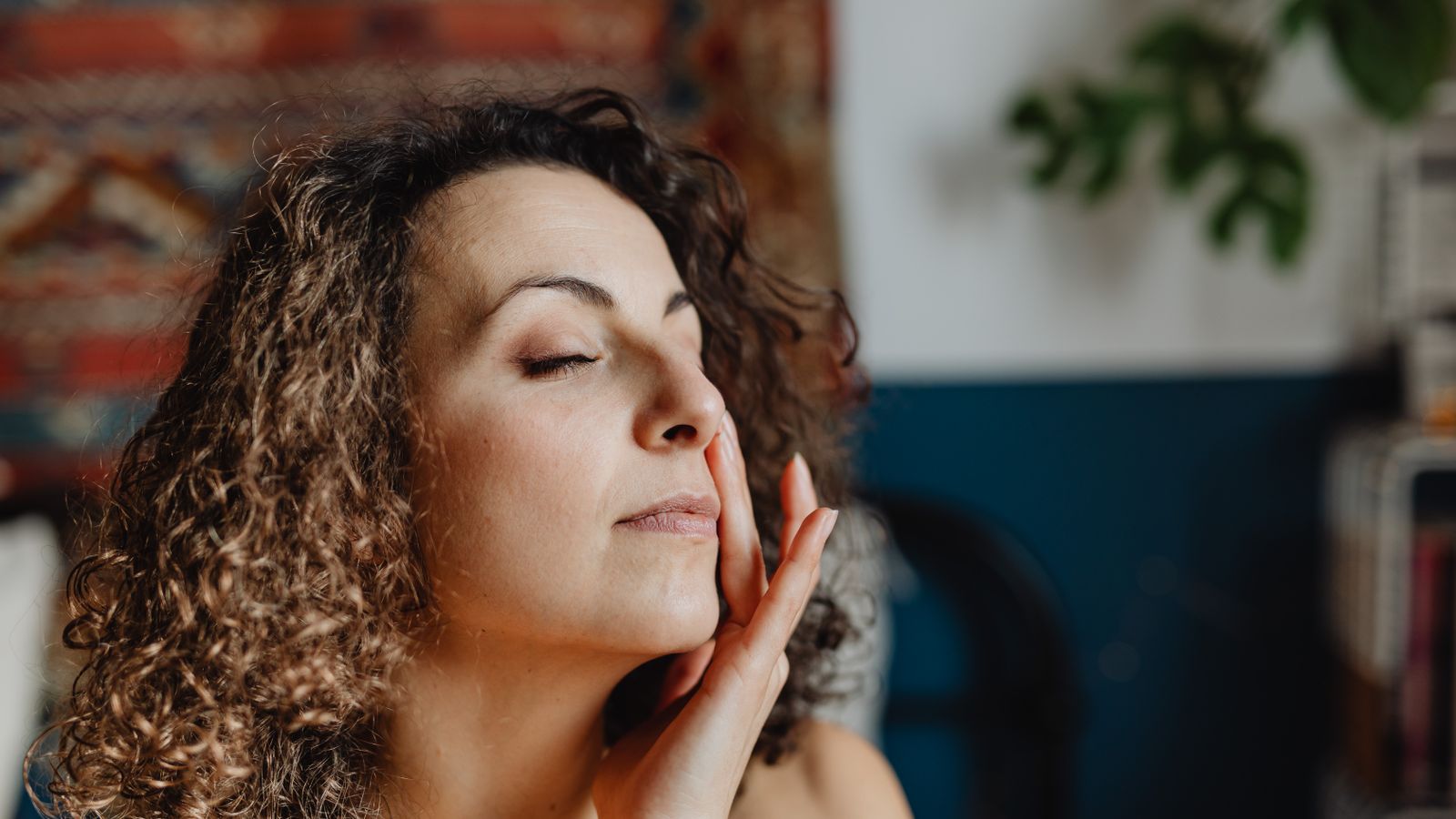 Relaxed woman with curly hair following a simple combination skin routine at home
