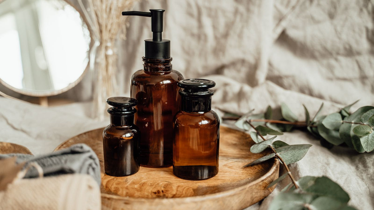 Amber glass bottles on a wooden tray, the kind of shelf where combining hair care products starts
