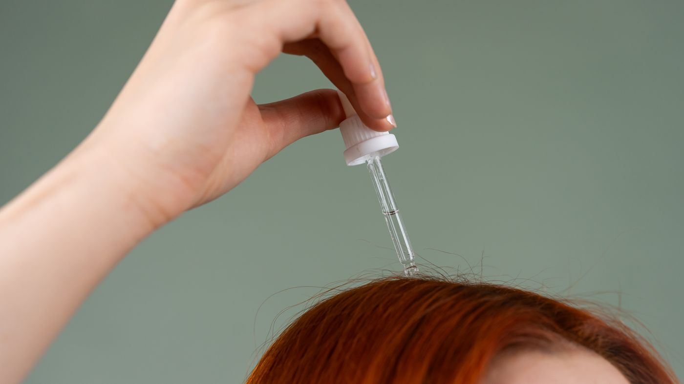 Applying a hair growth serum to the scalp with a dropper