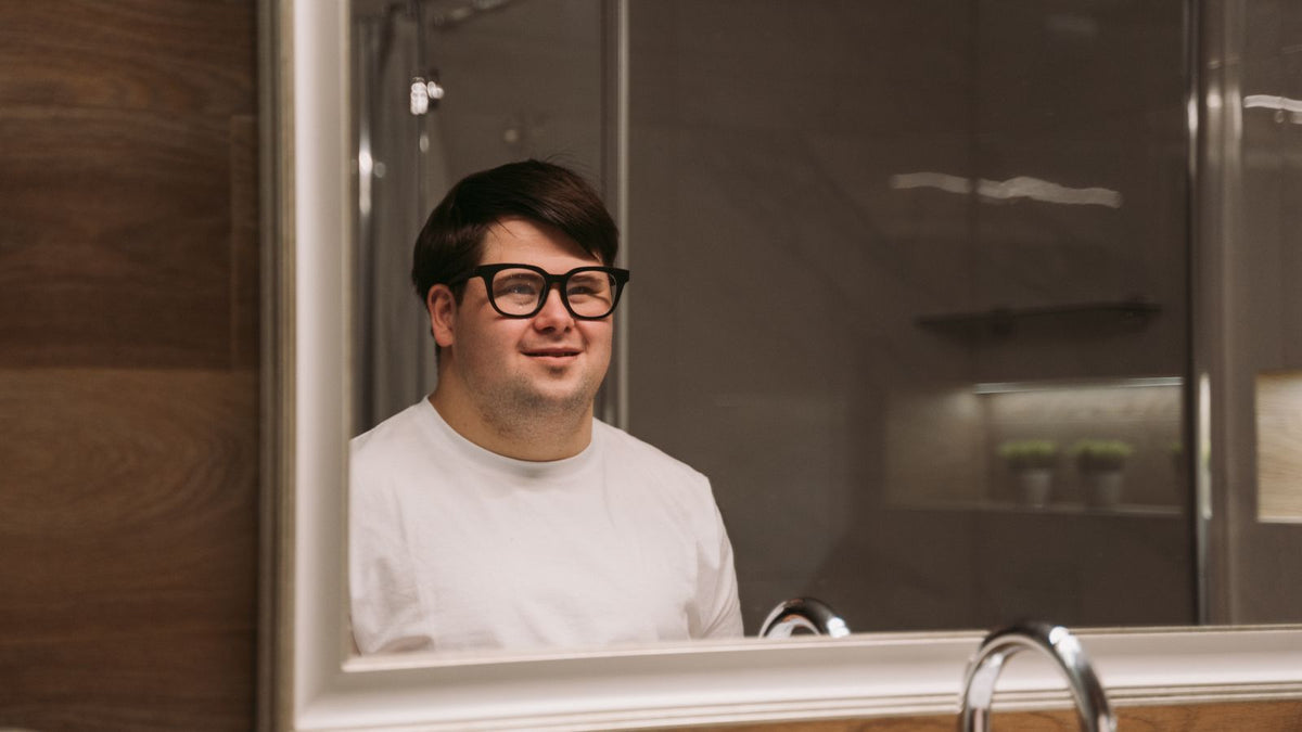 Man looking at his reflection in a bathroom mirror while wondering does masturbation cause hair loss