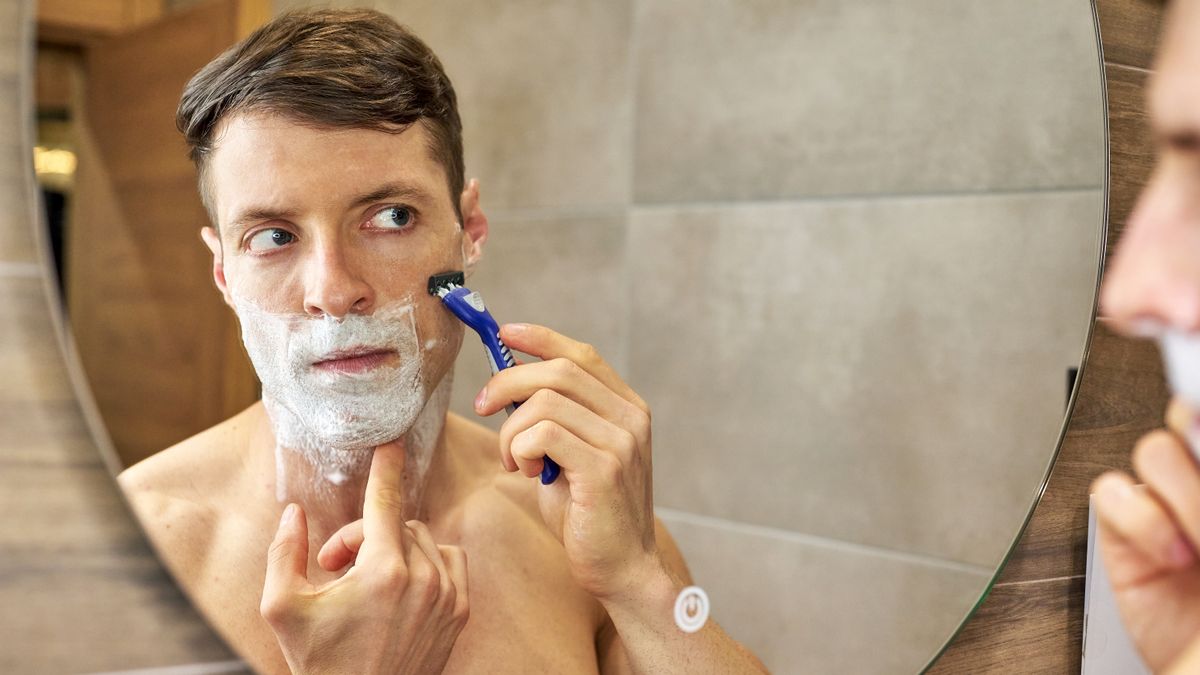 Man shaving at a bathroom mirror, the routine behind the question does shaving make hair grow back thicker