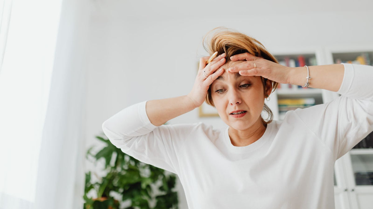 Worried woman with her hands on her forehead, wondering whether endocrine alopecia explains her thinning hair