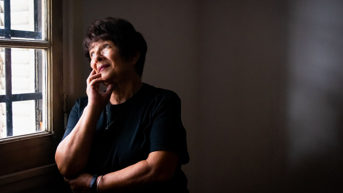 Thoughtful older woman looking out of a window, wondering whether estrogen dominance explains her symptoms