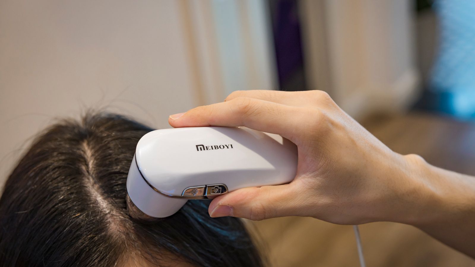 Scalp being examined with a handheld device, the setting in which exosome therapy is offered for hair