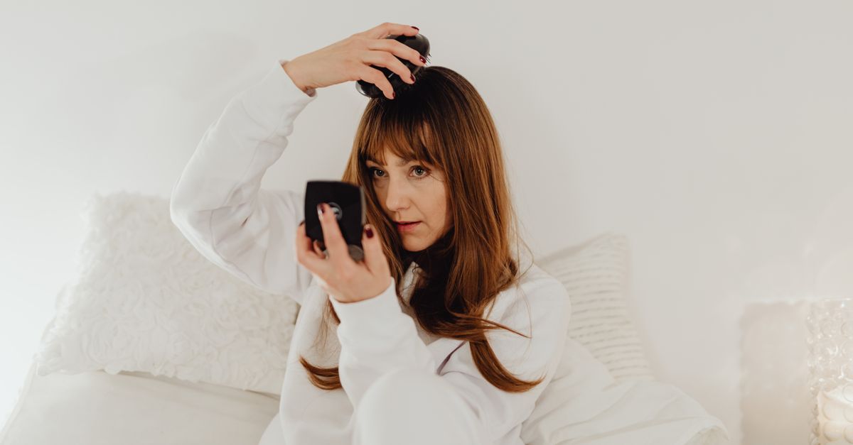 Woman brushing her hair while checking her parting for female pattern hair loss