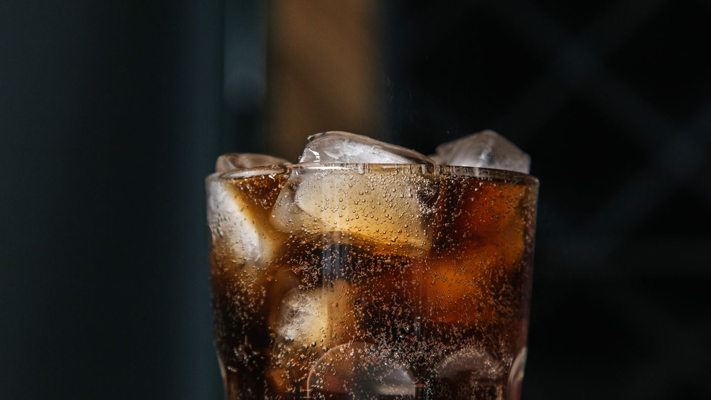 Fizzy sugary drink in a glass with ice, the main source of the fructose linked to insulin resistance