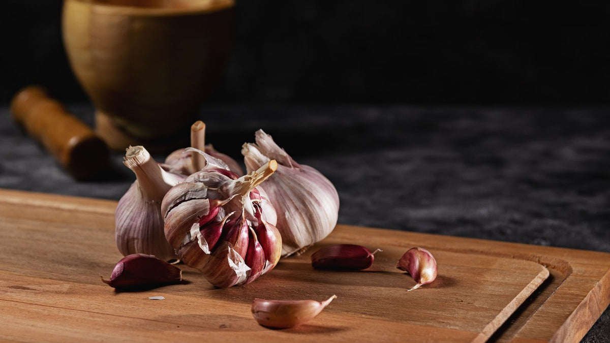 Garlic bulbs and cloves on a wooden board, the kitchen remedy behind garlic for hair growth