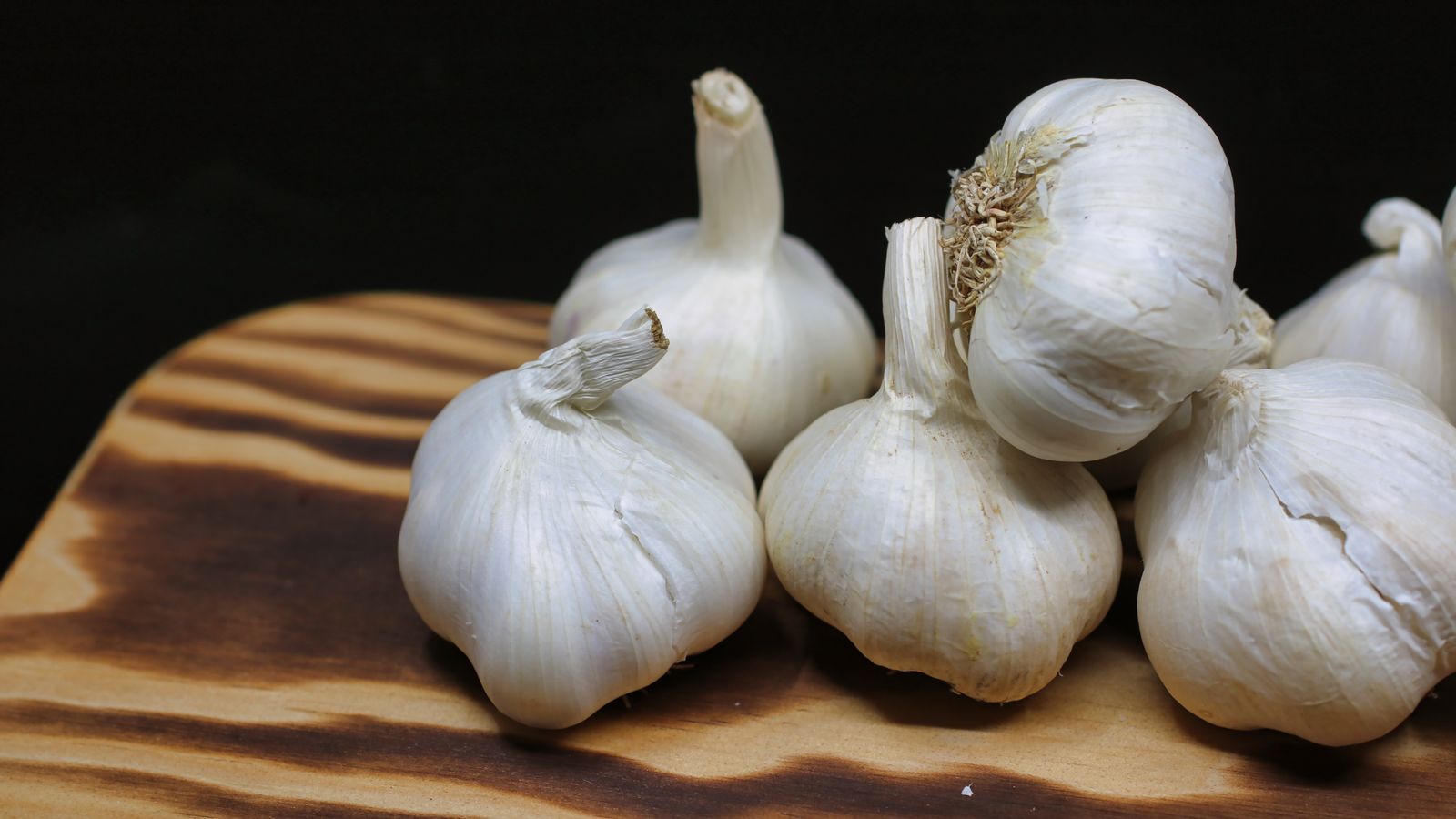 Fresh garlic bulbs on a wooden board, the whole food behind most garlic health benefits claims