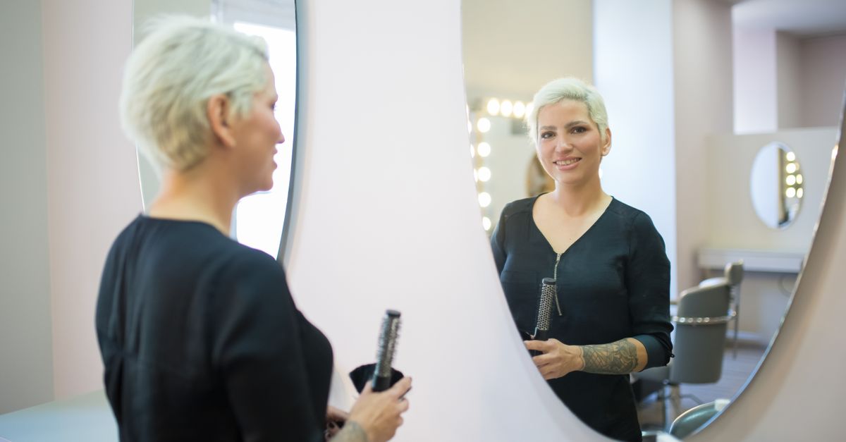Woman checking her hair in a mirror, assessing hair after stopping birth control