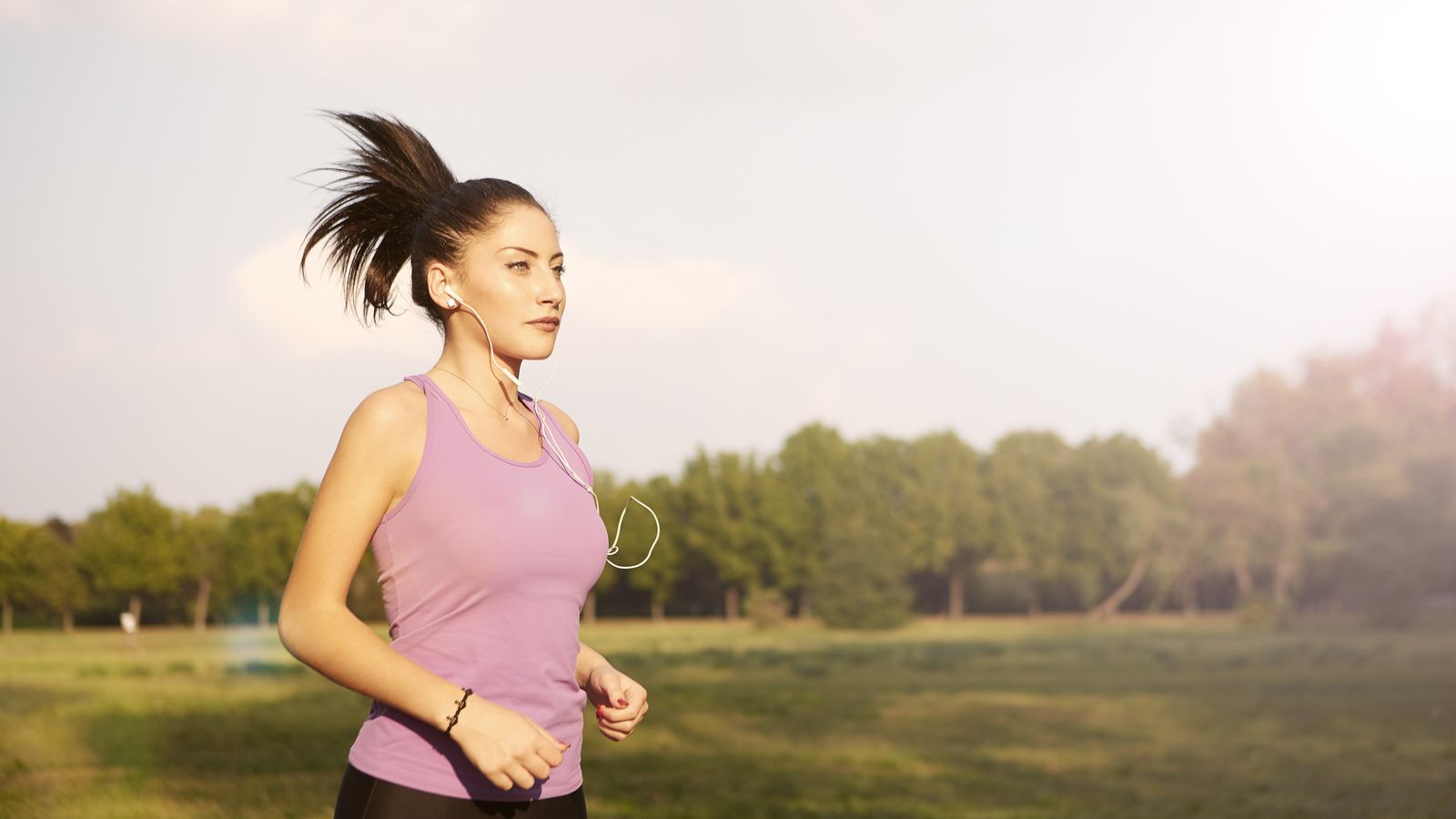 Woman jogging outdoors in sportswear, illustrating hair care after exercise and sweating