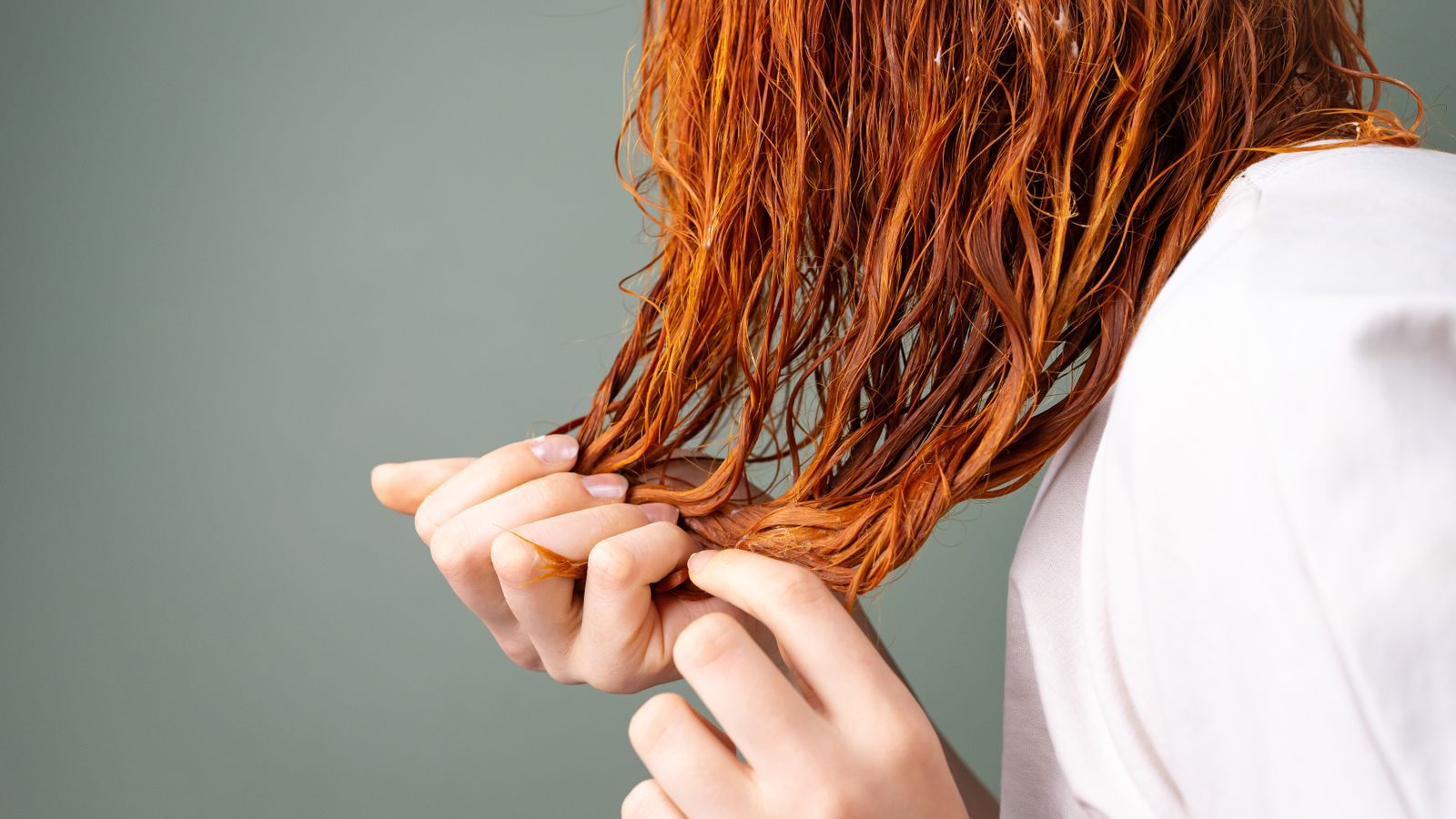 Close-up of a hair strand held between the fingers, the simplest way to test hair elasticity