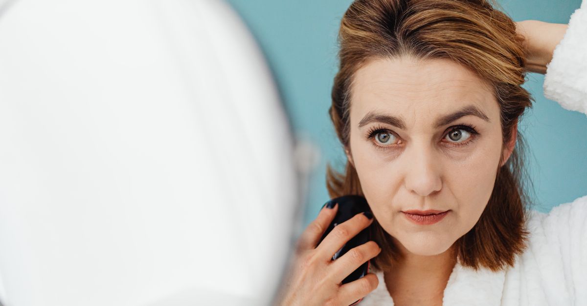 Woman styling her hair at the mirror during hair shedding recovery