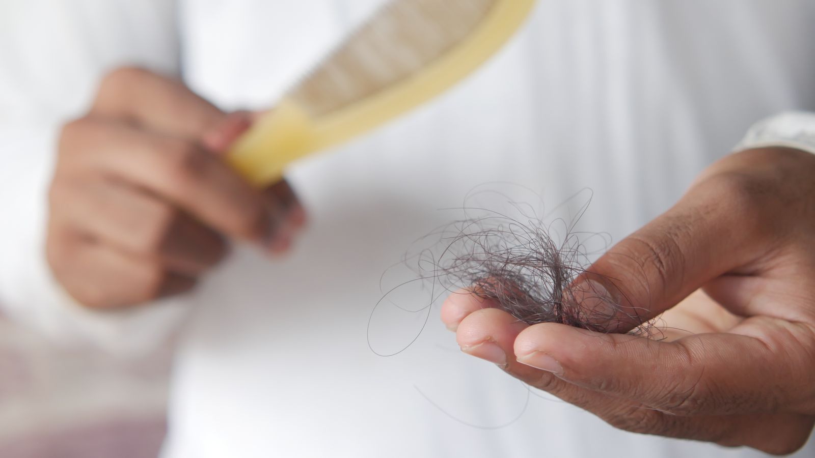 Comb holding shed strands, illustrating the hormone therapy hair loss some people notice after starting treatment