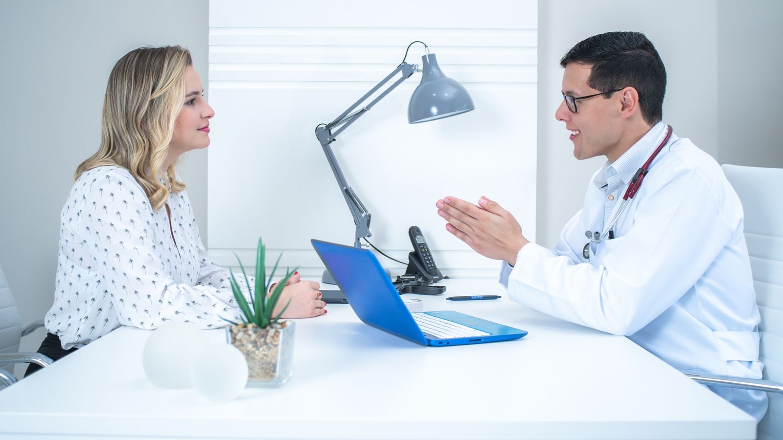 Doctor consulting a patient in a bright modern medical office about hormone therapy hair restoration options