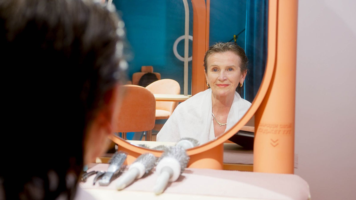 Woman checking her hair in a mirror while tracking hormone therapy hair shedding