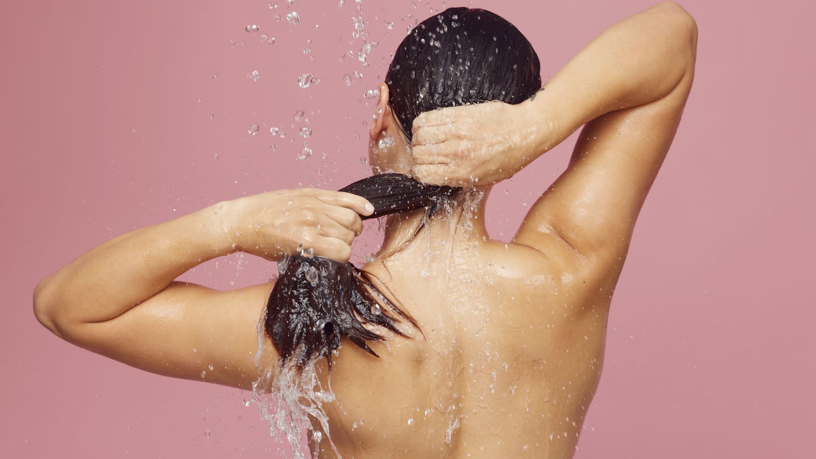 Woman washing her long hair in the shower, the starting point for how to choose a shampoo