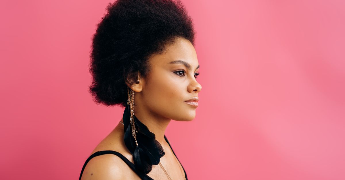 Profile portrait of a woman with afro textured hair, the result of learning how to grow an afro through length retention