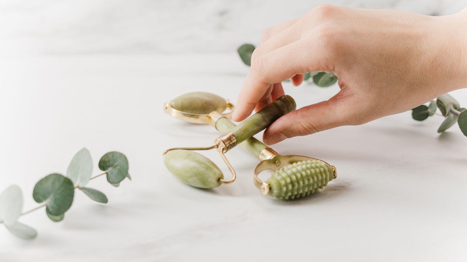 Hands holding a skincare roller tool on marble, illustrating how to use a derma stamp for hair growth safely