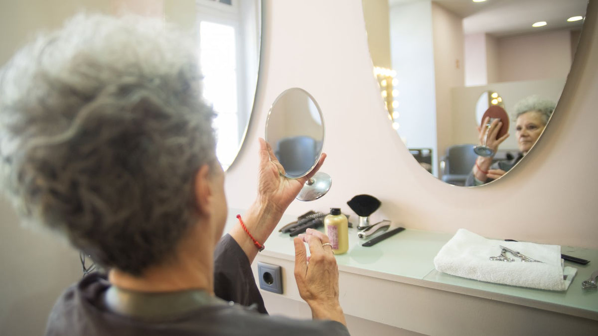 Woman checking her hair in a salon mirror, one of the simplest HRT hair biomarkers