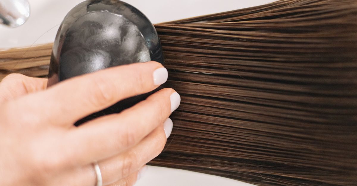 Woman brushing long brown hair, tracking changes through the HRT hair cycle