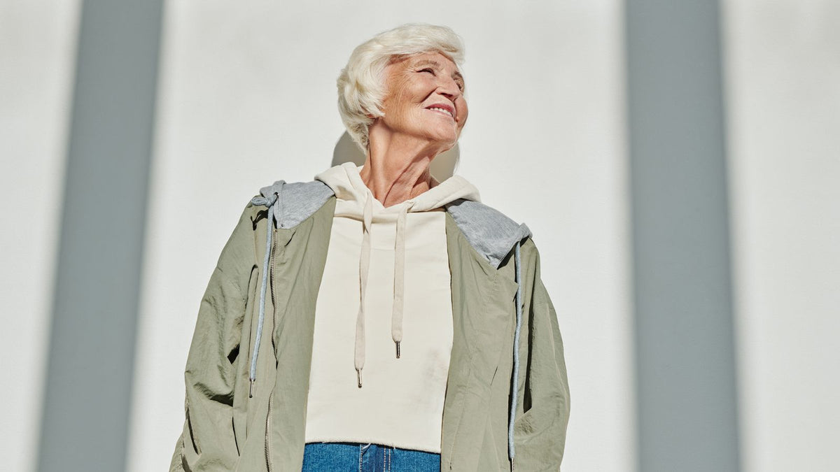 Smiling older woman outdoors in the sun, curious about HRT responsiveness and her hair