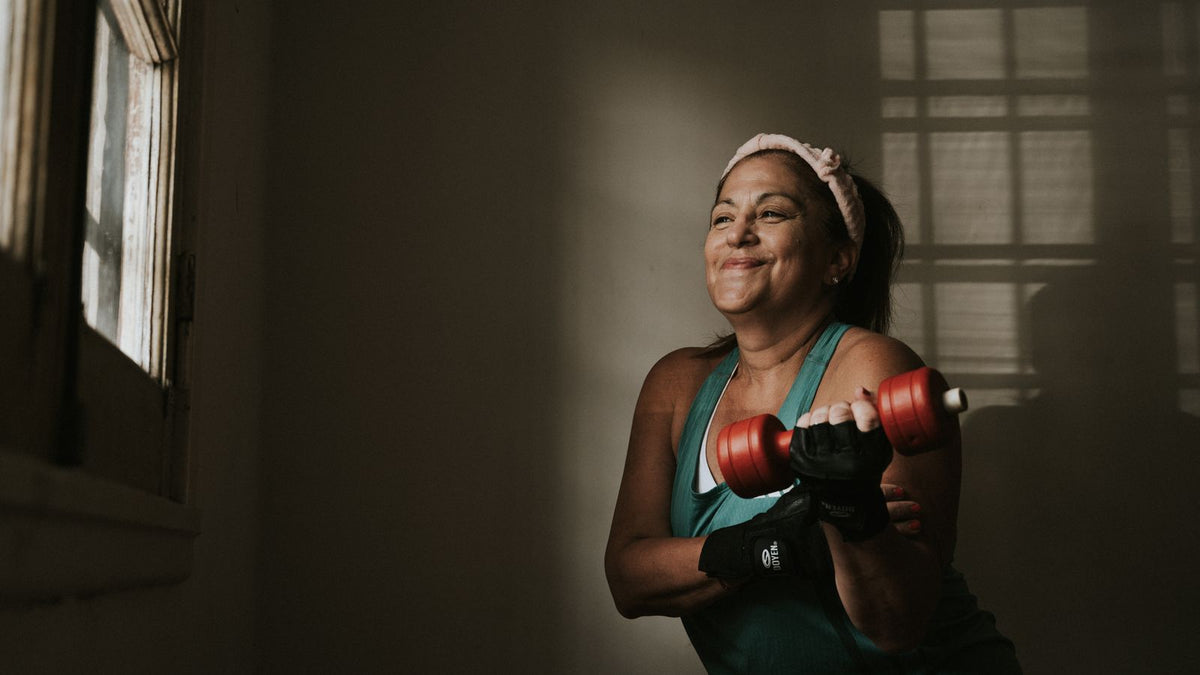Confident middle aged woman lifting dumbbells indoors, the strength training that improves insulin resistance