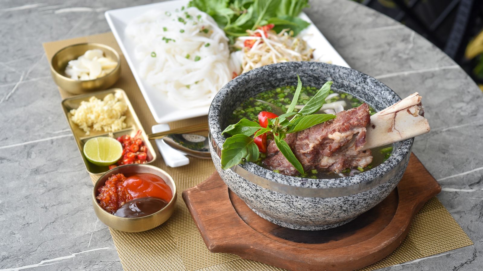 A bowl of beef bone broth with noodles and herbs, illustrating whether bone broth is good for hair growth