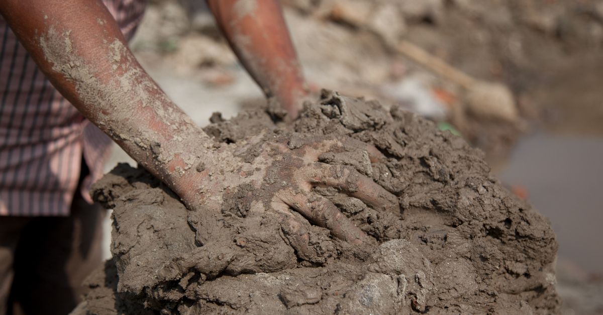 Close up of hands working with wet clay, the substance involved when asking is eating clay harmful