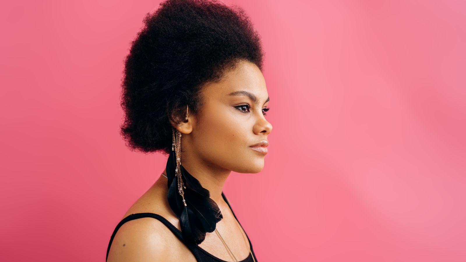 A woman with afro textured hair against a pink background, the hair type asking is eco gel bad for your hair