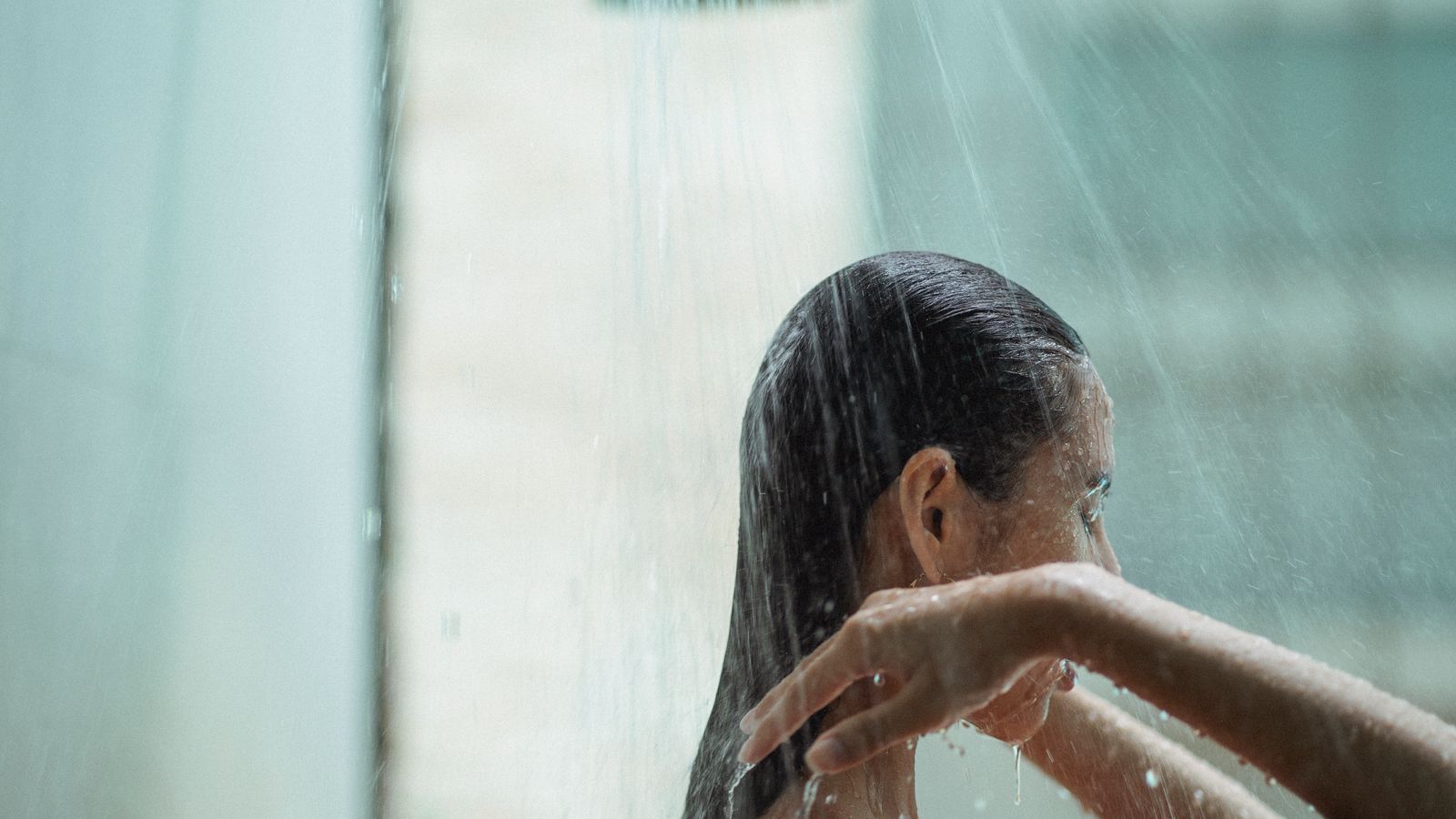 Woman with wet hair in the shower, wondering is it ok to wet your hair everyday