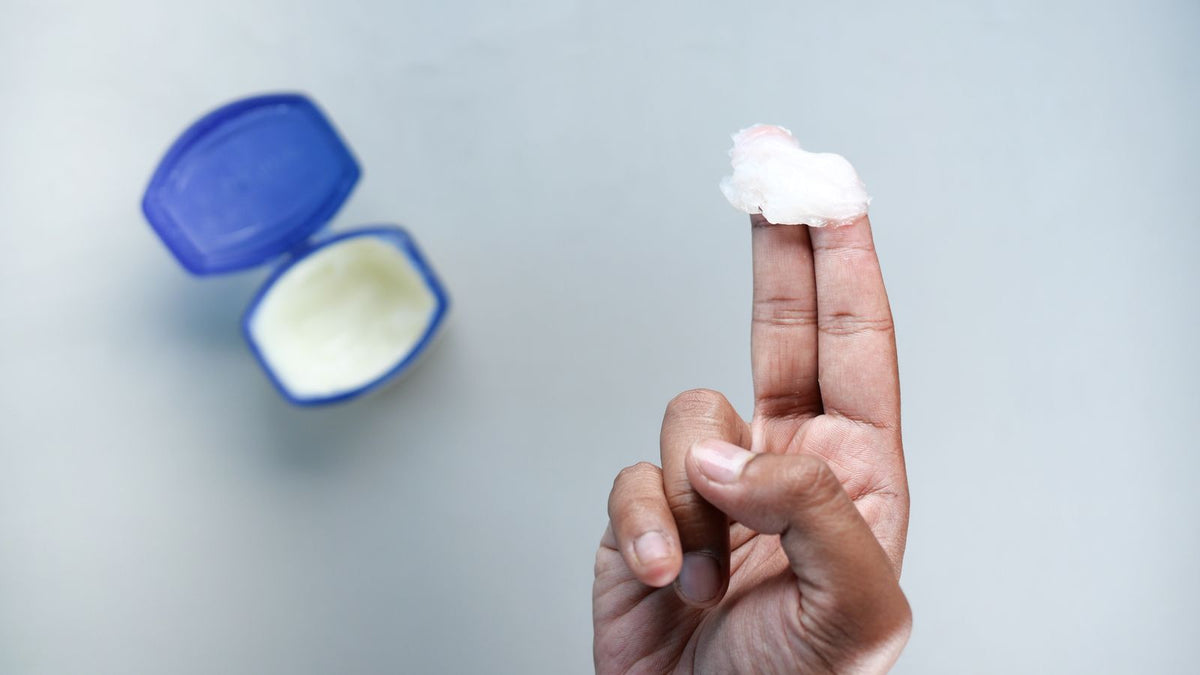 Petroleum jelly on a fingertip beside an open jar, the ingredient behind the question is petrolatum bad for hair